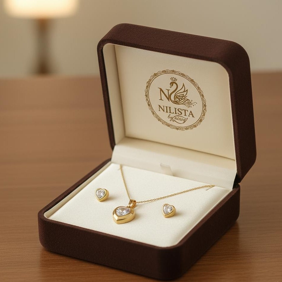 Gold jewelry set in a 'NILISTA' branded box on a wooden surface.