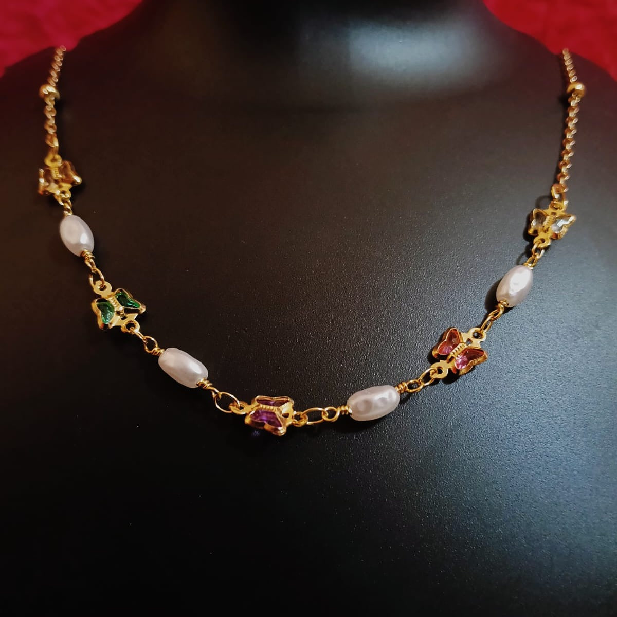 Gold necklace with pearls and gemstones on a dark background