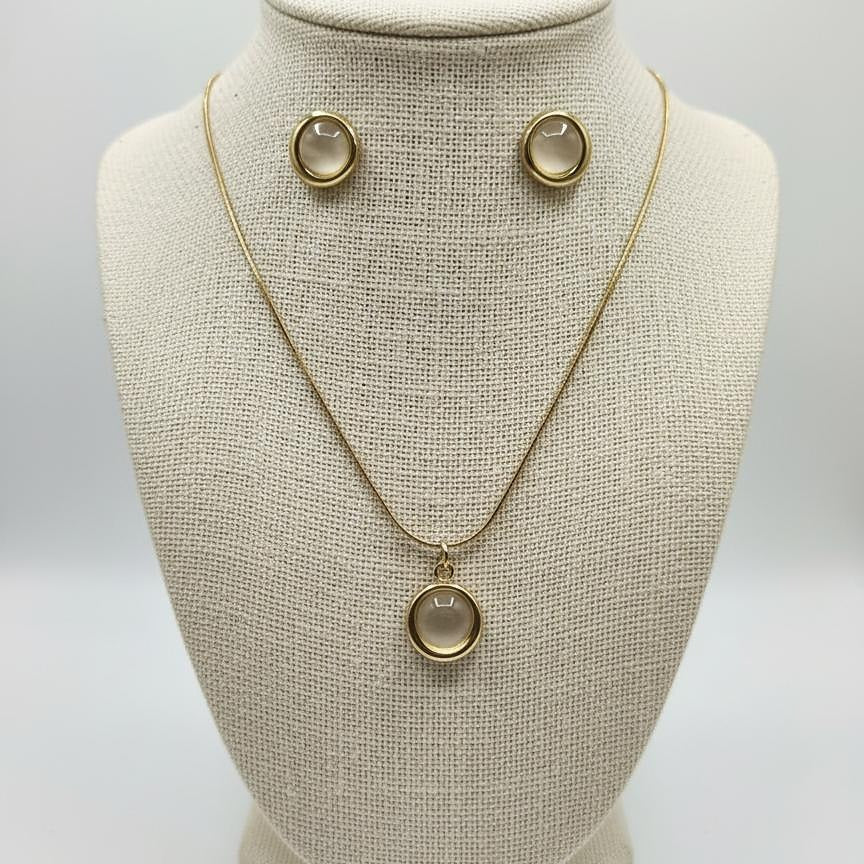 Gold necklace with pendant on a mannequin bust against a gray background