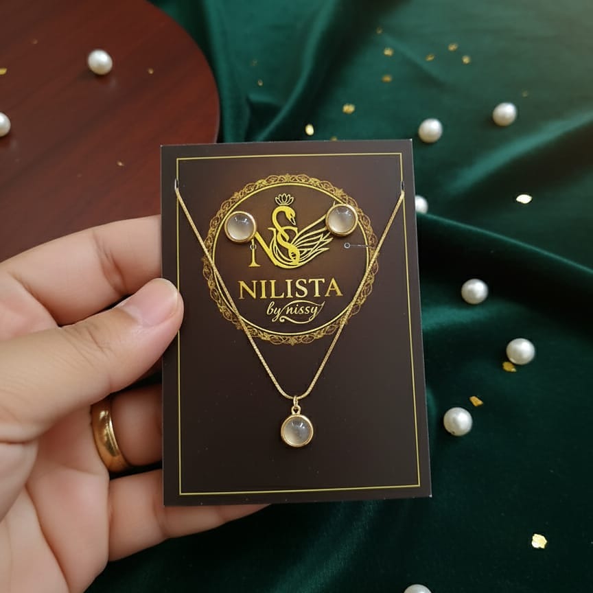Jewelry card with 'NILISTA by nissy' design held by a hand on a green fabric background.