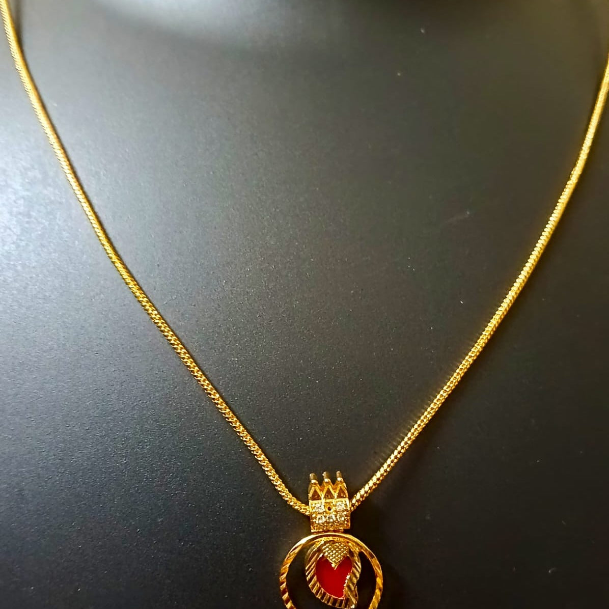 Gold necklace with a red pendant 