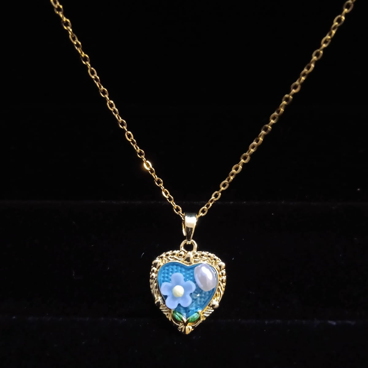 Heart-shaped pendant with floral design on a gold chain