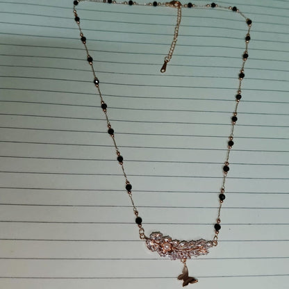 Necklace with black beads and a butterfly pendant on lined paper