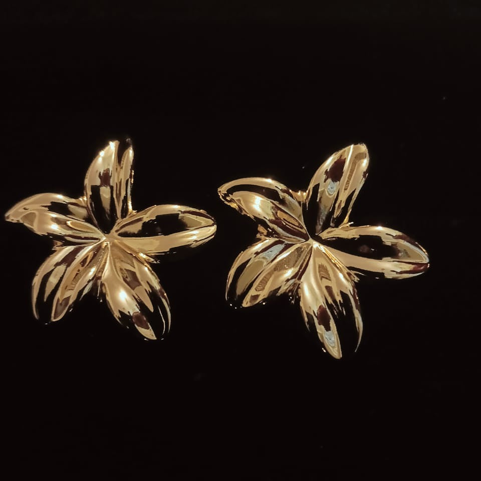 Pair of gold flower-shaped earrings on a black background