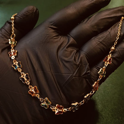 Gold chain with colorful pendants held by a gloved hand on a dark background