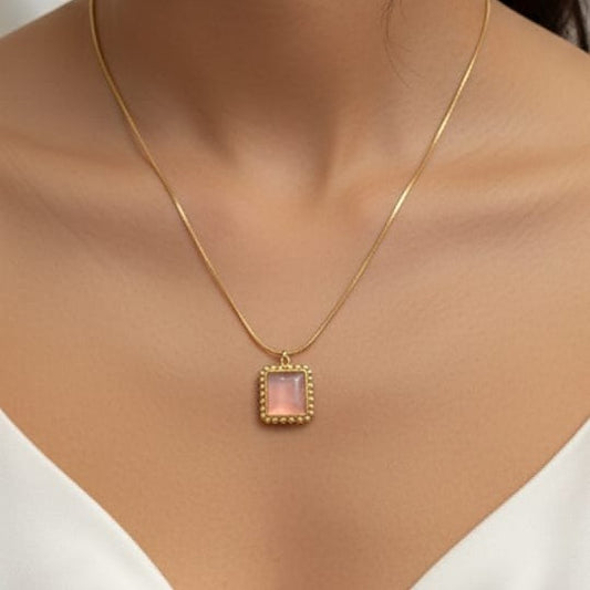 Gold necklace with a pink pendant on a mannequin